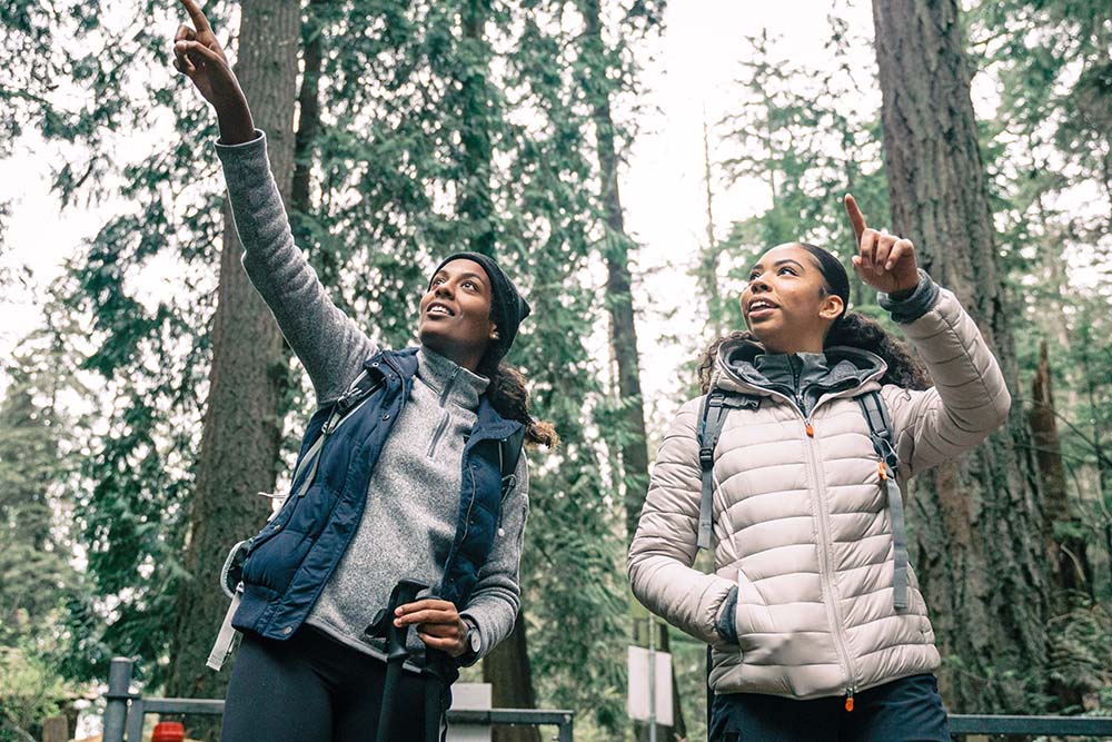 2 women pointing at something on a hike.